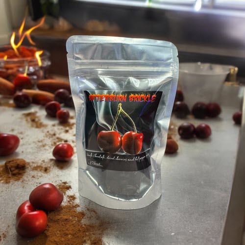 afterburn brickle bag on counter with cherries, spices and fire in background